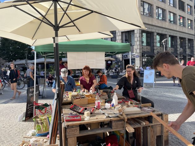 Eine Gruppe vom Menschen beim Reparieren von Gegenständen auf dem Stadtplatz.